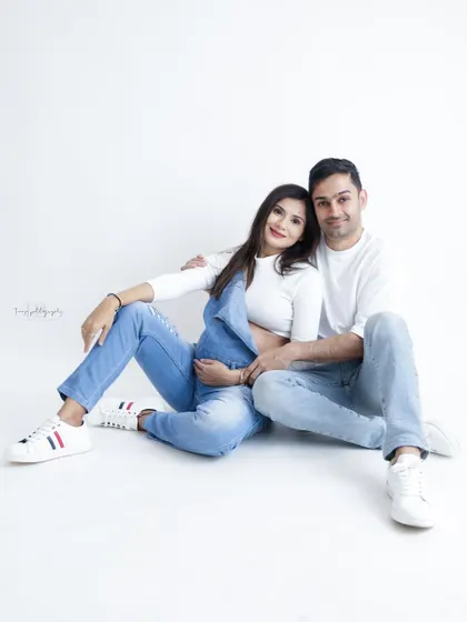 A relaxed and happy couple's portrait in matching white tops and jeans. Their easy smiles and comfortable pose make for a beautiful, natural photo.