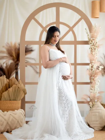 A serene solo portrait of a mom-to-be in a delicate white lace and tulle gown, set against our popular boho window arch.