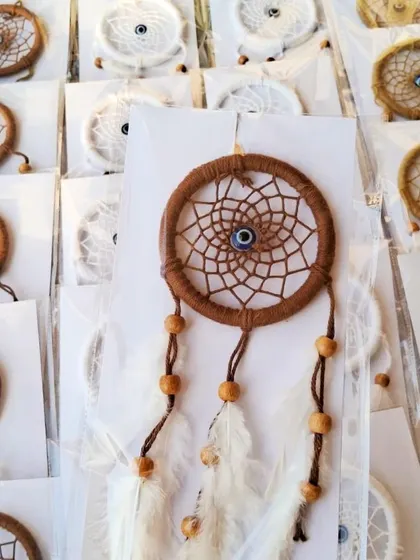 A close-up of the brown mini dreamcatcher with its delicate white feathers and wooden beads.