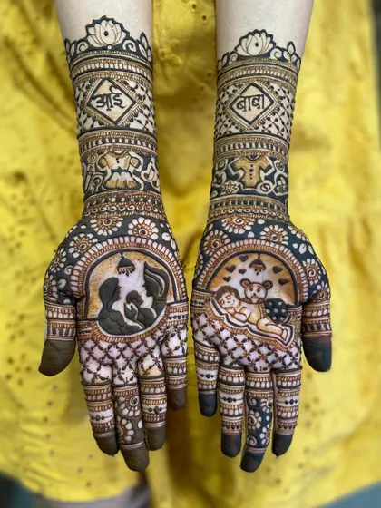 A beautiful maternity mehandi featuring a silhouette of a mother cradling her bump and a sleeping baby, with 'आई' and 'बाबा' written on the arms.
