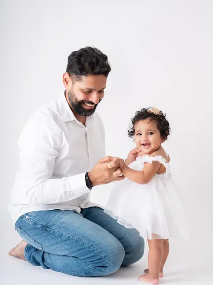 Another angle of dad helping his daughter stand. It captures the milestone from a different perspective, focusing on their interaction.
