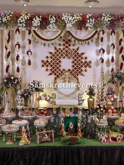 For a truly royal feel, this setup features a rich maroon and cream color palette. The intricate backdrop pattern and symmetrical arrangement of offerings create a look of pure elegance and luxury.