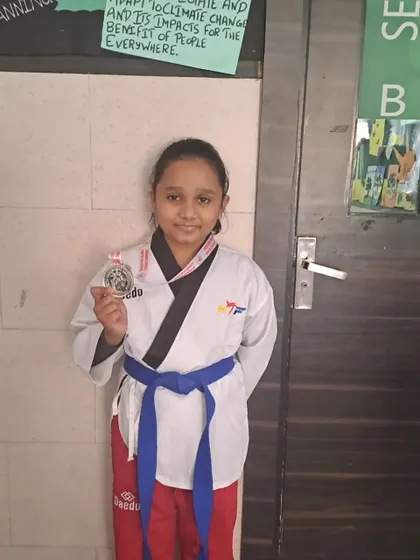 A student proudly displays her Poomsae silver medal from the Delhi State Championship.