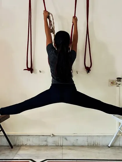 Using chairs and wall ropes for support, this young student practices a full middle split. We use various props in our gymnastics training to help kids achieve their flexibility goals safely.