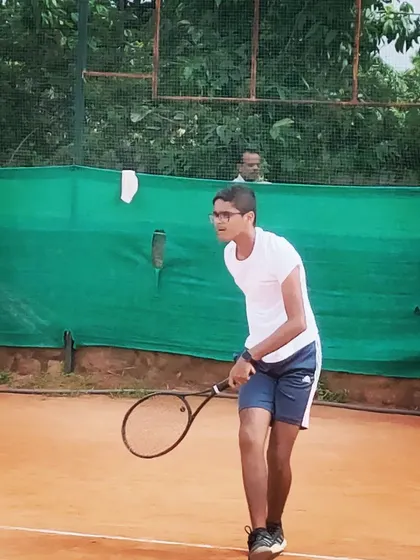 A junior player prepares to return a serve, showing his readiness and focus during an AITA U-14 tournament match.