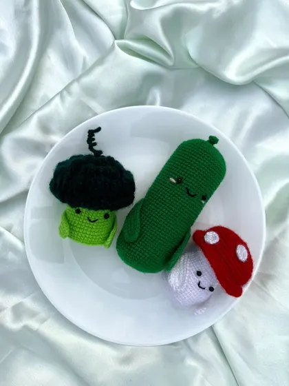 I also enjoy making quirky and fun crochet creations, like this set of smiling vegetables: a broccoli, a pickle, and a mushroom.