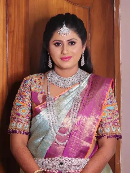 Amrutha looking stunning in a pastel blue and purple saree for her reception. Her makeup is glamorous with a focus on glowing skin and is paired with beautiful diamond jewelry.
