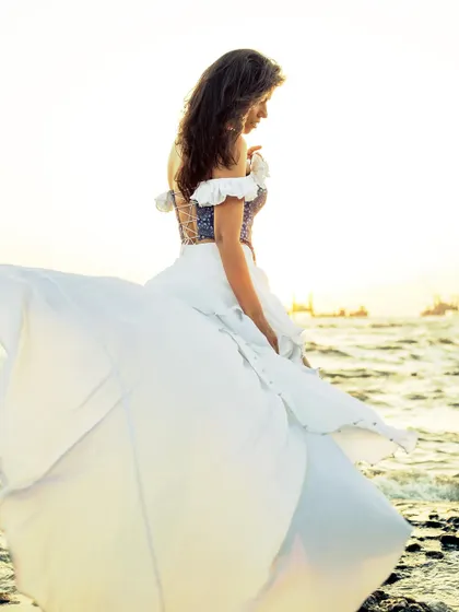 An ethereal, backlit shot where the white skirt of the dress catches the wind, creating a dreamy and cinematic image.