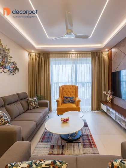This living room setup features a TV unit with a textured back panel and geometric inlays. The neutral sofa is accented with a bright yellow armchair, adding a vibrant pop of color to the space.