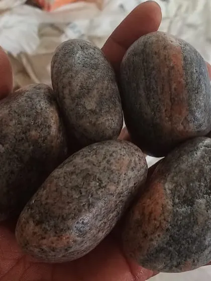 A handful of larger, multi-colored unpolished pebbles, showing their natural stripes and patterns.