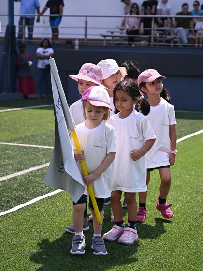 The flag bearer leads her classmates in the march past.