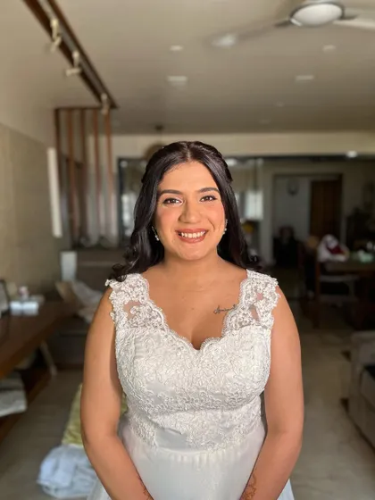 A romantic half-updo with a delicate braid and pearl accents for a white wedding. The soft curls complete this dreamy and elegant bridal look.
