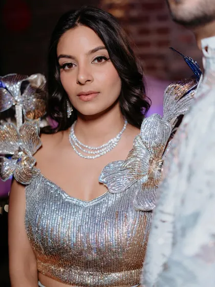 A close-up of the Sangeet look. A defined eye and a neutral lip let the shimmering outfit and the bride's happy expression be the focus.