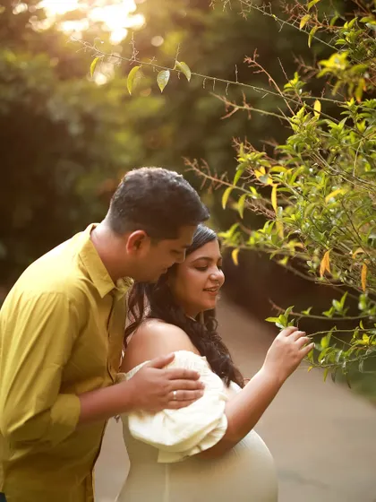 A quiet moment during an outdoor maternity shoot. The golden sunlight filters through the trees as they share a peaceful moment, nurturing their love and new beginnings.