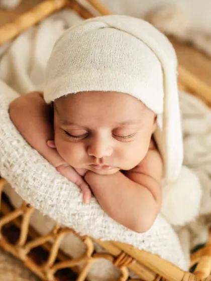 A beautiful close-up of a baby in the classic "chin on hands" pose. This highlights their delicate features, from their long eyelashes to their tiny fingers.