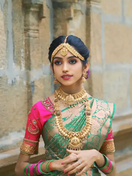 A beautiful portrait of a bride in our green and pink silk saree. The traditional temple background complements the classic bridal attire, available for rent for your wedding day.