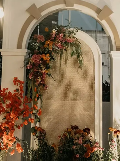 A close-up of the floral decor on the mandap arches. We used a mix of bright red bougainvillea and other colorful blooms, with a rattan screen adding a touch of texture.