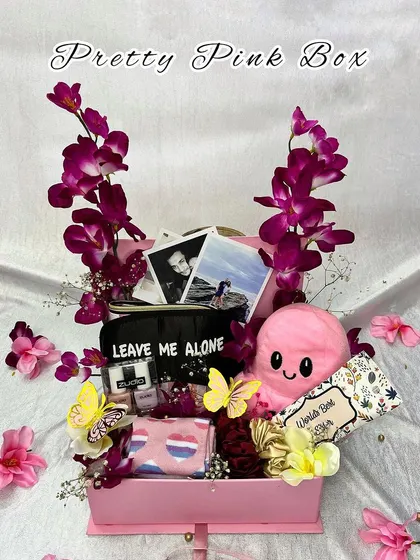 The "Pretty Pink Box" is a dream for anyone who loves pink. This hamper is overflowing with goodies like a plush octopus toy, photos, an eye mask, and other fun accessories, all accented with orchids.