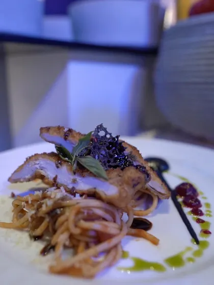 A modern pasta dish, where the noodles are topped with perfectly cooked chicken and a delicate, artistic garnish. This is how we elevate a simple concept into a fine-dining experience.