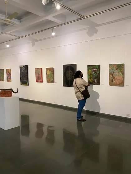 A visitor looking closely at one of Unnikrishnan C's more somber portraits.