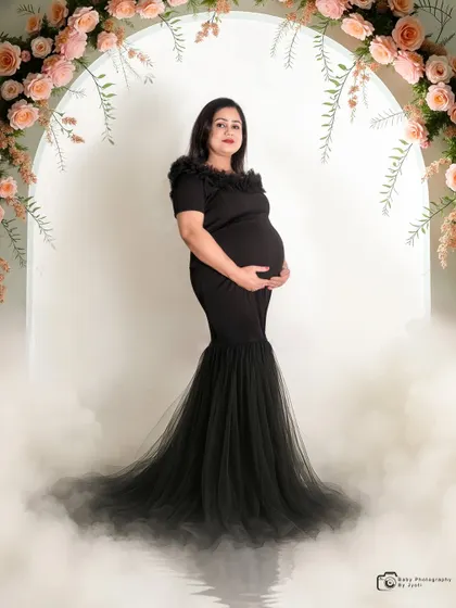 A dramatic solo portrait in a black mermaid-style gown. The floral arch and smoke effect add a touch of glamour and mystery.