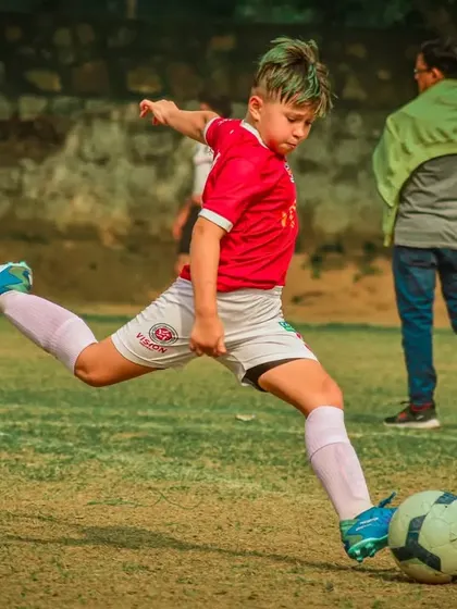 A young player with green and blonde hair takes a powerful shot.