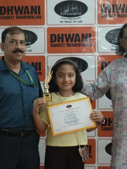 A senior guru blesses and presents an award to a young student.