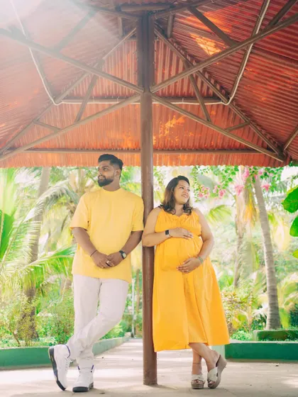 Finding interesting structures in an outdoor location can add a unique touch to your photos. Here, the couple poses under a shaded gazebo, creating a relaxed and stylish portrait during their maternity session.