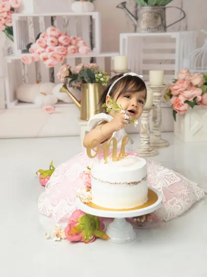 A playful moment trying to grab the "one" cake topper. These candid interactions are what make each cakesmash session unique and full of personality.