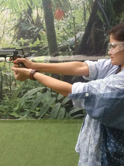 A visitor enjoying her first practical shooting experience with a pistol. Our instructors are always on hand to guide you on proper grip and stance for a safe and enjoyable session.