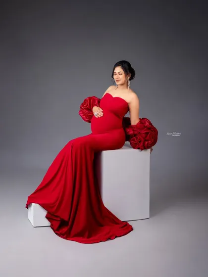 A seated portrait that highlights the intricate details of the gown's sleeves and the serene expression of the mom-to-be.