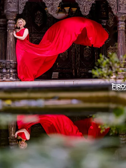 A beautiful reflection shot of a model in a red dress against our ornate wooden doors.