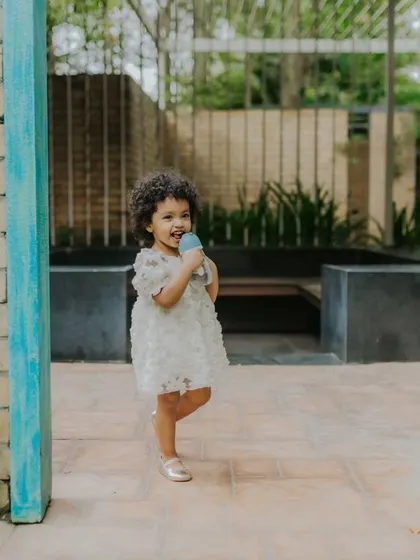 A duplicate of image 4, showing the little girl with her sipper in a lovely garden setting. Outdoor shoots are great for capturing children's natural curiosity and playfulness.