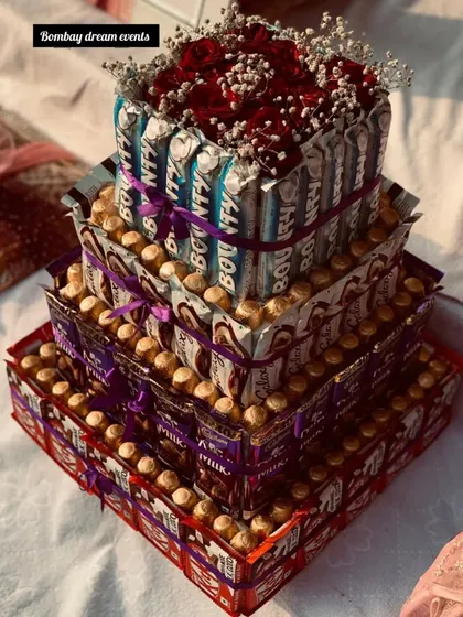 A custom three-tiered chocolate tower made with Snickers, Bounty, and other favorites, crowned with a small bouquet of red roses. I can create these with any chocolates of your choice.