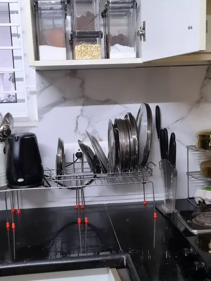 This is how we tackled a tiny kitchen with a lot of items. By elevating everything on risers and racks, we freed up the entire counter for cooking, turning a stressful space into a functional one.