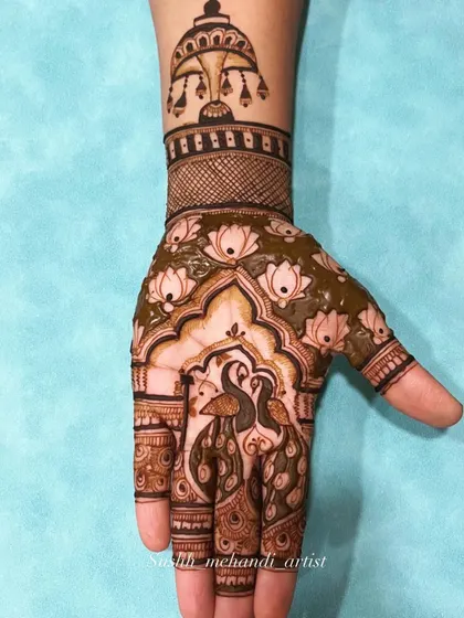 A half-finished design showing the rich green of the fresh henna paste. This design has two peacocks under a beautiful canopy.