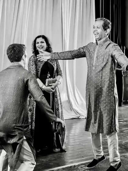 The father of the bride acts as a "wall," playfully blocking the groom's brother during the shoe-stealing game.