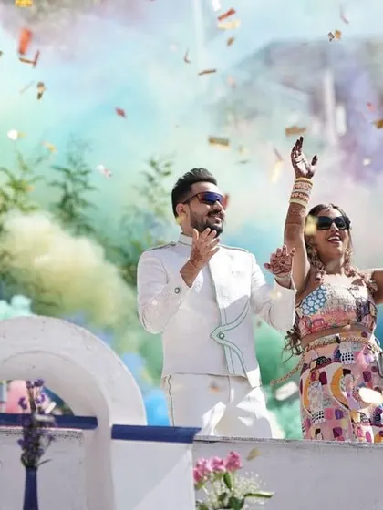 The happy couple enjoying their grand carnival entry, surrounded by a cloud of colorful smoke and confetti. These are the moments of pure joy we love to create.