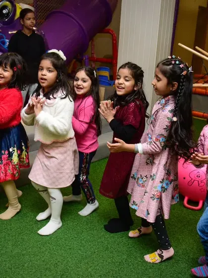 Game ready! A group of girls claps and sings along, fully engaged in the party activities and ready for what's next.