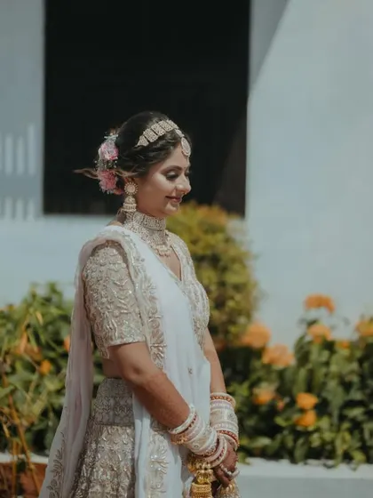 A candid shot of the bride during her Mamera ceremony, looking serene in a white and gold lehenga. The makeup is soft and ethereal to match the vibe of the event.