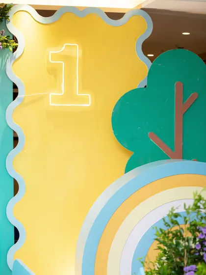 A close-up of the light-up number '1' and the hand-painted rainbow, key elements of the travel-themed backdrop.