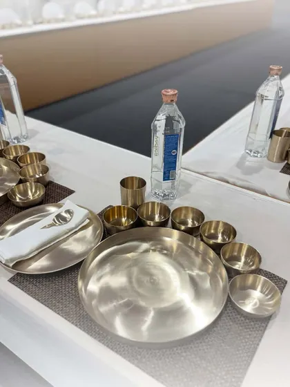 A beautifully set table with our traditional Kansa (bronze) thali sets. This showcases our commitment to heritage and providing an authentic, luxurious dining experience.