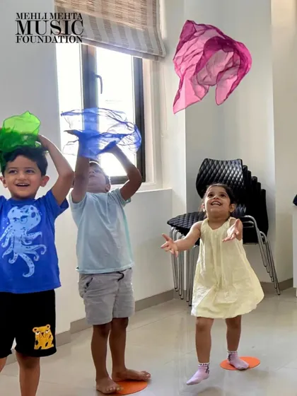The pure, uninhibited joy of music and movement in our Discover Music class. We use colorful props like these scarves to help our youngest students feel the rhythm and express themselves, making learning an exciting and playful experience.