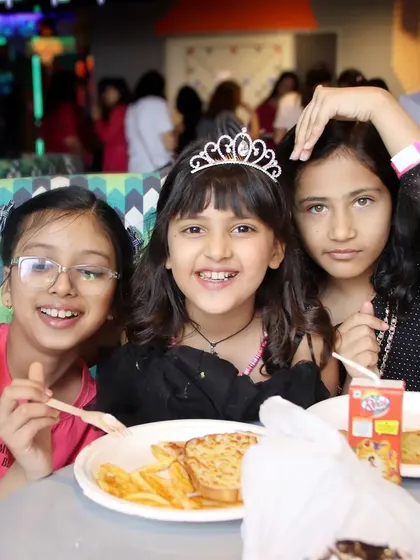 Three young girls laughing and enjoying a meal at a birthday party. These candid shots of guests having fun are a key part of our event coverage.