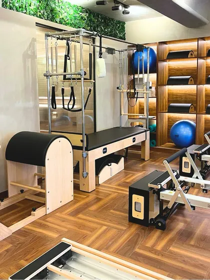 A corner of our studio featuring the Cadillac, Ladder Barrel, and Reformers. We offer a complete range of classical apparatus for a comprehensive practice.