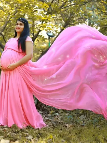 This pink flying gown is a classic choice for maternity shoots, creating a soft and dreamy look in this park setting.