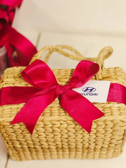 The final touch. A team member ties the perfect pink bow on a Kauna basket for the Hyundai order, ensuring every detail is just right.