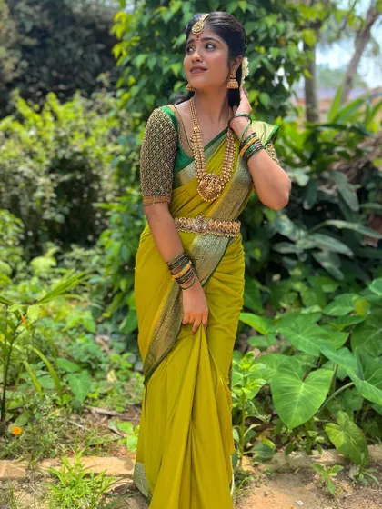 This green blouse features a fully beaded sleeve design, adding a modern texture to a traditional silk saree look.