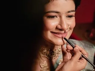 A candid, behind-the-scenes moment during an engagement makeup session. This artistic shot captures the final touch of lipstick application, highlighting the detail and care I put into creating a perfect, soft glam look for my client.