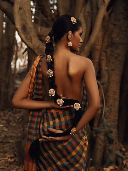 A back portrait focusing on the traditional hair adornments and the beautiful texture of the handloom saree.